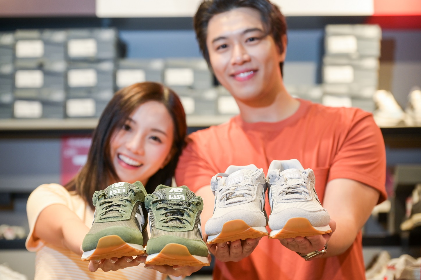 A happy couple is each holding a pair of sneakers.